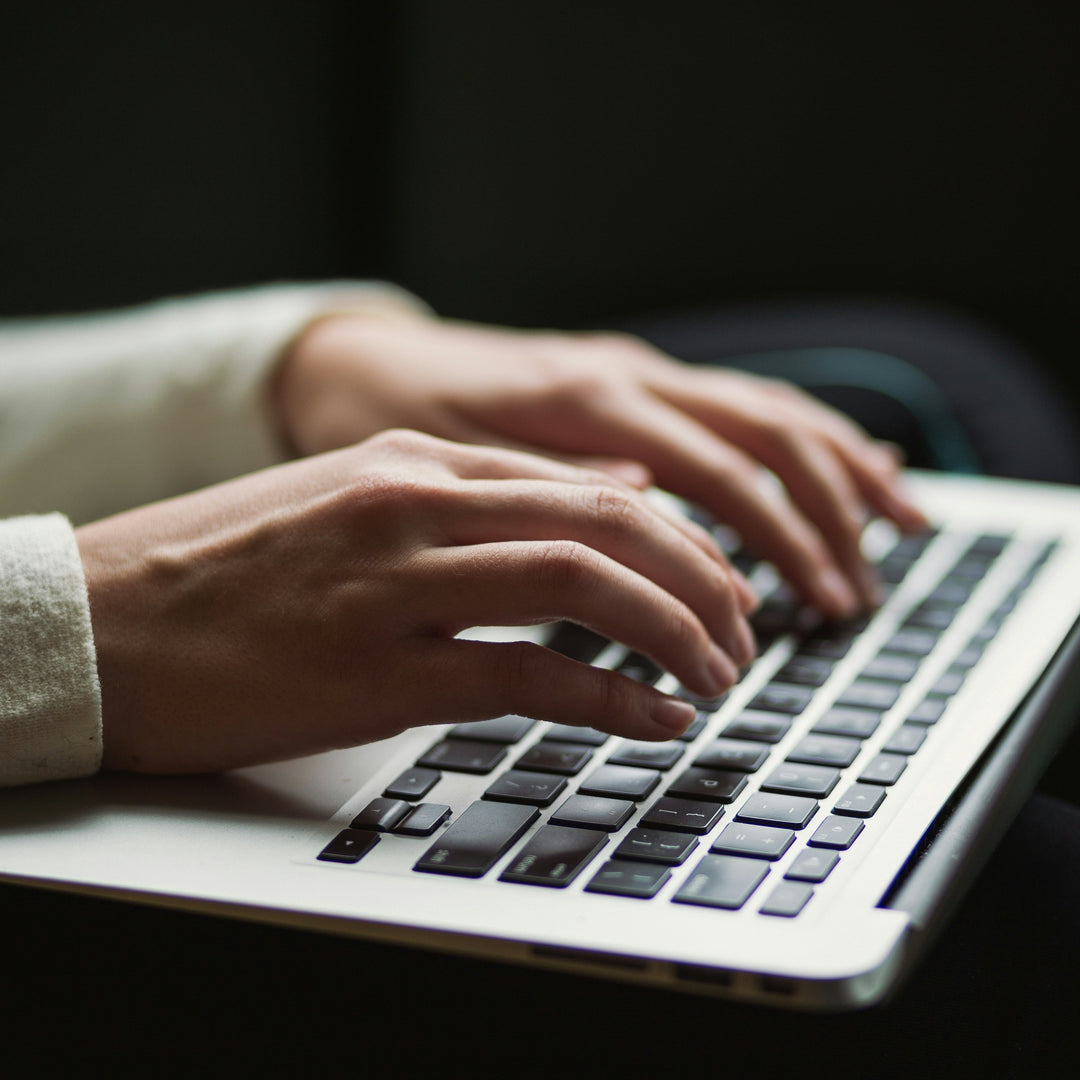 Hands typing on a silver laptop keyboard in a flexible coworking space by The SoPurist.