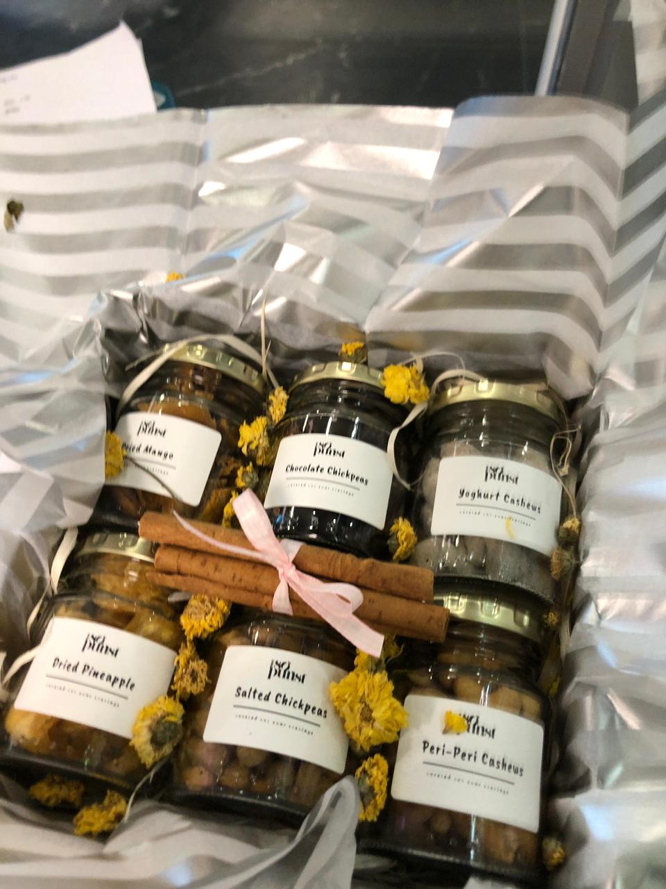 Open SoPurist gift box with six labelled glass jars, cinnamon and yellow flowers